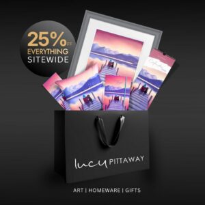 Black Lucy Pittaway gift bag filled with A Pawfect Place by the Water artwork, cushions, stationery and a 2025 calendar, with a “25% off everything sitewide” badge.